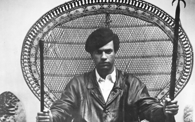 Poster shows portrait photograph by Blair Stapp of Huey Newton sitting in a rattan throne chair with a rifle and a spear. This photo was published in The Black Panther, Vol. 1, No. 6, November 23, 1967. (Blair Stapp, Public domain, via Wikimedia Commons)