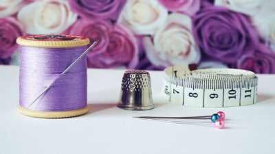 spool of purple thread near needle thimble and measuring tape
