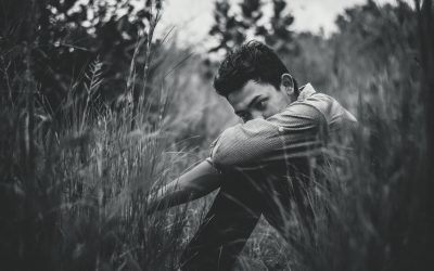 monochrome photo of man sitting on grass