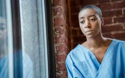 upset black woman in blue medical robe looking at window in daytime
