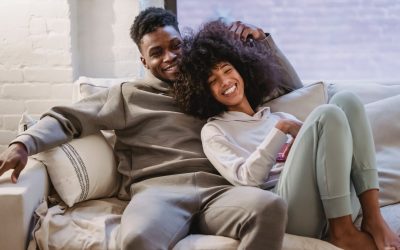 beloved african american couple cuddling and smiling on couch