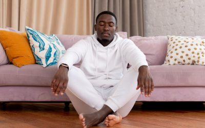 tranquil black man sitting with closed eyes and crossed legs on floor