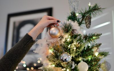 person holding beige bauble near christmas tree
