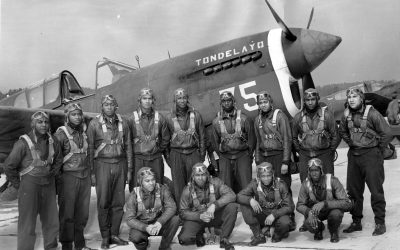 Thirteen members of Tuskegee Airmen class 43C posing in front of an airplane.
